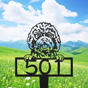 May include: A black metal yard sign featuring a dog design with the number "501". The dog has a fluffy, textured appearance with black and white fur and blue and green accents. The sign is set in a field with mountains in the background.
