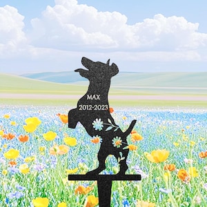 Könnte beinhalten: Schwarze Metall-Gartenschild mit Hundesilhouette, mit dem Namen "MAX" und den Jahren "2012-2023". Der Hund steht auf den Hinterbeinen, mit floralen Akzenten. Der Hintergrund zeigt eine Blumenwiese unter blauem Himmel.