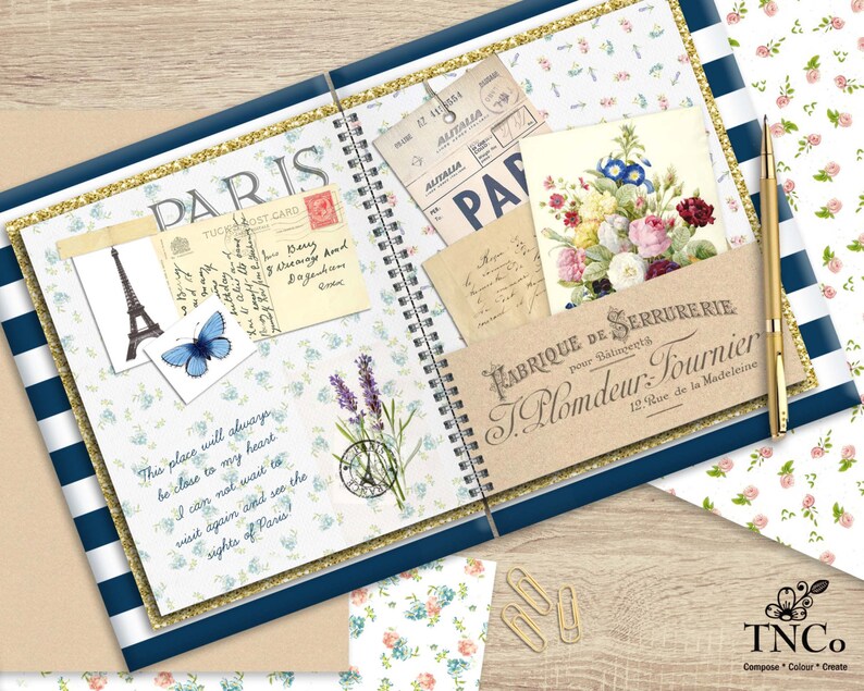 May include: A blue and gold spiral bound journal with a floral design and a quote about Paris. The journal has a pocket on the front cover with a vintage postcard and a small bouquet of flowers. The journal is open to a page with a quote about Paris and a lavender sprig.