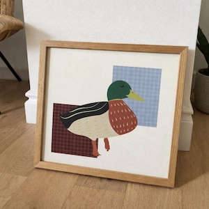 May include: A framed art print depicting a stylized duck illustration. The duck has a green head, yellow beak, and a red and white body. The background features a blue and white checked pattern and a burgundy checked pattern.
