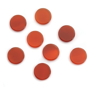 Peut inclure: Huit pierres précieuses rondes en cornaline, polies et de couleurs rouge-orangé variées, sur fond blanc. Ces pierres sont idéales pour la création de bijoux ou d'autres projets artisanaux. Chaque pierre est un disque lisse et plat.