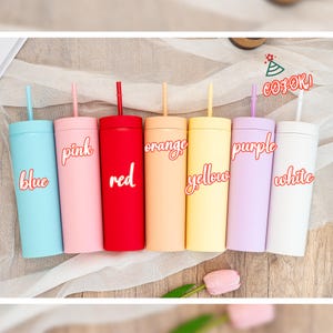 May include: A collection of seven colorful tumblers with straws. Each tumbler is a different color: blue, pink, red, orange, yellow, purple, and white. The color names are written on each tumbler in a cursive font.