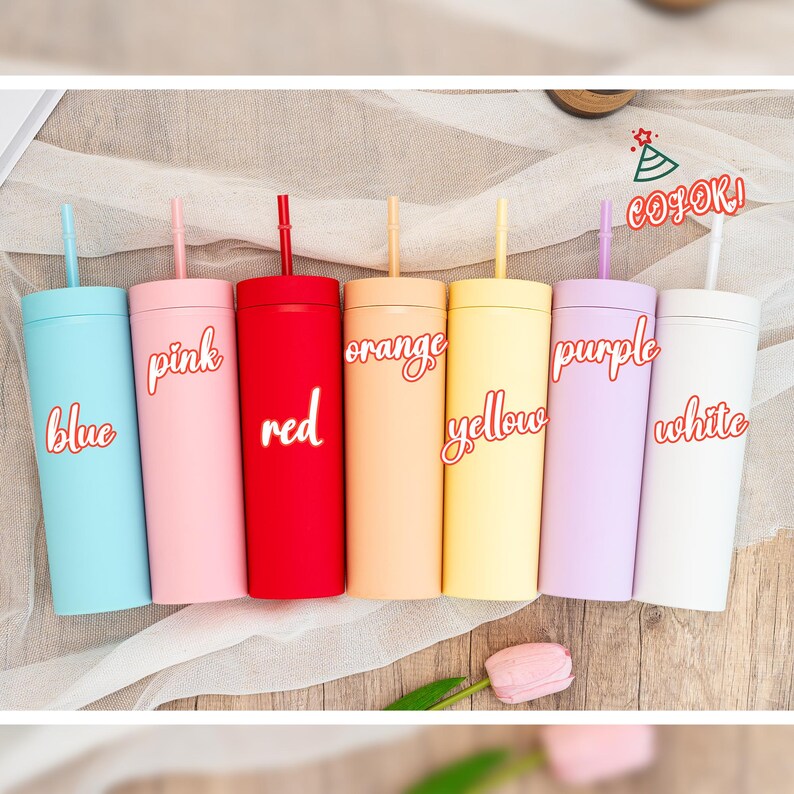 May include: A collection of seven colorful tumblers with straws. Each tumbler is a different color: blue, pink, red, orange, yellow, purple, and white. The color names are written on each tumbler in a cursive font.