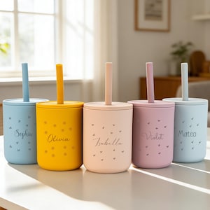 May include: Five colorful personalized tumblers with lids and straws. The tumblers are in shades of blue, yellow, pink, and purple. Each tumbler has a name printed on it: Sophia, Olivia, Isabella, Violet, and Mateo. The tumblers are decorated with small floral and heart patterns.