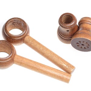 May include: Two wooden nutcrackers with handles. The nutcrackers have a round opening at the top and a carved design at the bottom.
