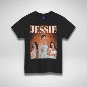 Może przedstawiać: Czarny t-shirt z grafiką retro przedstawiającą trzy kobiety i napis "JESSIE". Grafika wykorzystuje ciepłą paletę barw i ma estetykę vintage. T-shirt jest wykonany z miękkiego materiału.