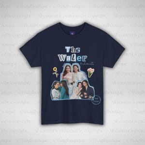 May include: A navy blue crew neck t-shirt with the text "The Water" and "Helenenta" printed on the front. The graphic includes images of women, a sunflower, and a bouquet. The shirt is made of a soft material.