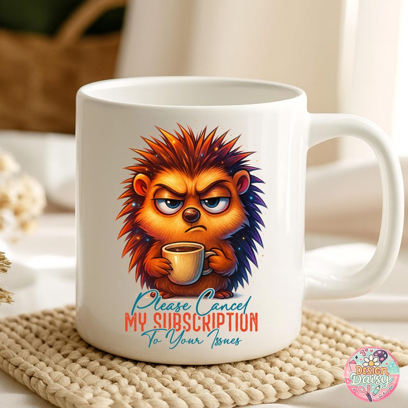 May include: White ceramic coffee mug featuring a grumpy cartoon hedgehog holding a coffee cup. The hedgehog has orange and brown quills, blue accents, and an angry expression. Text on the mug reads "Please Cancel My Subscription To Your Issues."