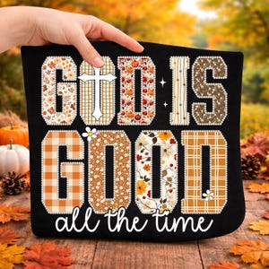 Puede incluir: Camiseta negra con la frase "GOD IS GOOD" en una fuente decorativa. Las letras están rellenas de patrones florales, a cuadros y de calabazas. La frase "all the time" está escrita en cursiva debajo.