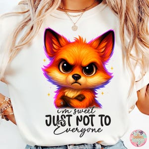 May include: White t-shirt featuring a cartoon fox with an angry expression. The fox is orange, red, and purple with crossed arms. The text "I'm sweet JUST NOT TO Everyone" is below the fox.