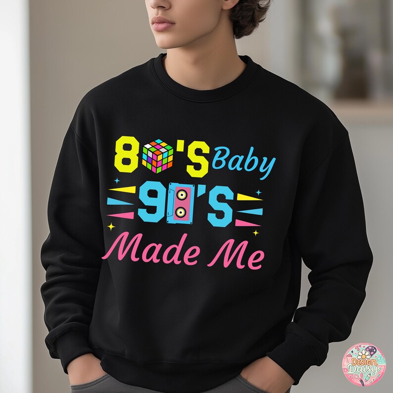 May include: Black sweatshirt with the text "80's Baby 90's Made Me" in bright colors. The design includes a Rubik's Cube, a boombox, and stars. The sweatshirt is a crew neck style.