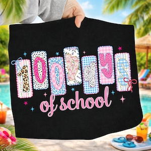 Könnte beinhalten: Schwarzes Strandtuch mit dem Schriftzug "100 days of school" in rosa. Die Zahlen sind mit verschiedenen Mustern wie Leopardenmuster und Vichy verziert. Das Tuch wird von einer Person gehalten.