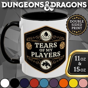 May include: White ceramic mug with a black interior and handle. The mug features a black and gold label with the text "TEARS OF MY PLAYERS" and "DUNGEONS & DRAGONS" branding. Available in 11 oz and 15 oz sizes.