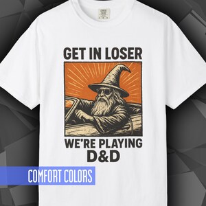 Comfort Colors T-shirt with a D&D funny meme/Dungeons & Dragons graphic. The shirt is 100% cotton, premium quality, available in 14 colors, unisex fit, plus size options. RPG tabletop role play gamer apparel. T-shirt featuring a wizard in a car and the text "Get In Loser We're Playing D&D".
