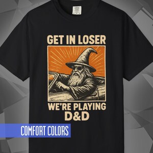 Comfort Colors T-shirt with a D&D funny meme/Dungeons & Dragons graphic. The shirt is 100% cotton, premium quality, available in 14 colors, unisex fit, plus size options. RPG tabletop role play gamer apparel. T-shirt featuring a wizard in a car and the text "Get In Loser We're Playing D&D".