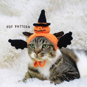May include: A tabby cat wearing a handmade Halloween costume. The costume includes an orange hat with a carved pumpkin and a black witch hat, along with black wings and an orange bow tie. The text "PDF PATTERN" is visible.