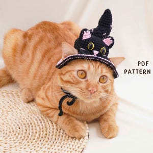 Peut inclure: Un chapeau de chat crocheté noir avec un design de chapeau de sorcière pointu, des oreilles intérieures roses, des yeux jaunes et un petit nez rose. Le chapeau comprend une mentonnière noire et le texte PDF PATTERN est imprimé en noir à droite.