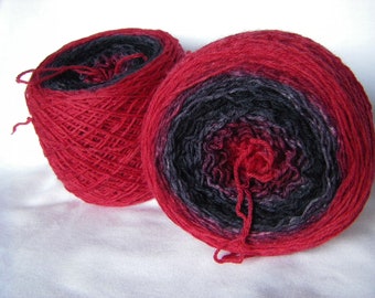 May include: Two skeins of yarn, one red and one with a black and red ombre pattern.