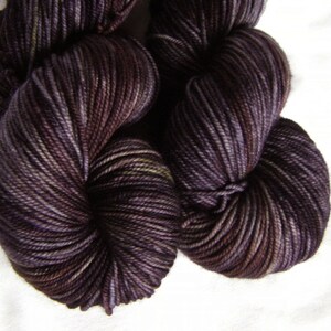 Peut inclure: Une pelote de fil de couleur violet fonc&eacute; avec de subtiles nuances de violet clair et de vert. Le fil est torsad&eacute; en un n&oelig;ud l&acirc;che.