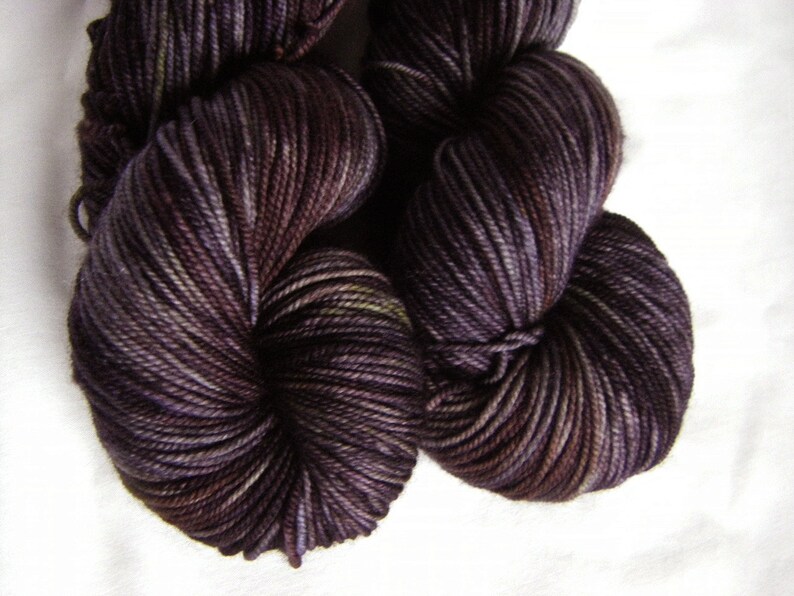 Peut inclure: Une pelote de fil de couleur violet fonc&eacute; avec de subtiles nuances de violet clair et de vert. Le fil est torsad&eacute; en un n&oelig;ud l&acirc;che.