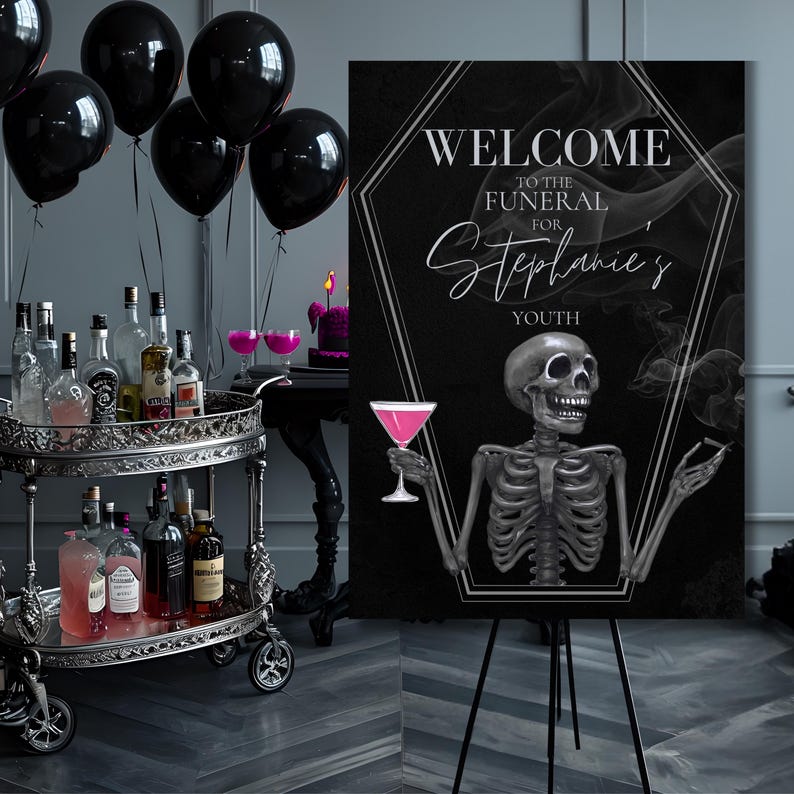 May include: A black sign with the text "WELCOME TO THE FUNERAL FOR Stephanie's YOUTH" and a skeleton holding a pink cocktail. The sign is on a black easel, with black balloons and a bar cart in the background.