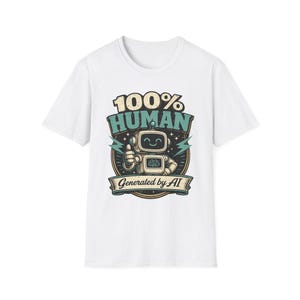 Peut inclure: Un t-shirt blanc à manches courtes avec une impression graphique représentant un robot souriant faisant un pouce levé. Le texte indique 100% HUMAN au-dessus du robot et Generated by AI sur une bannière en dessous, en bleu sarcelle et crème.