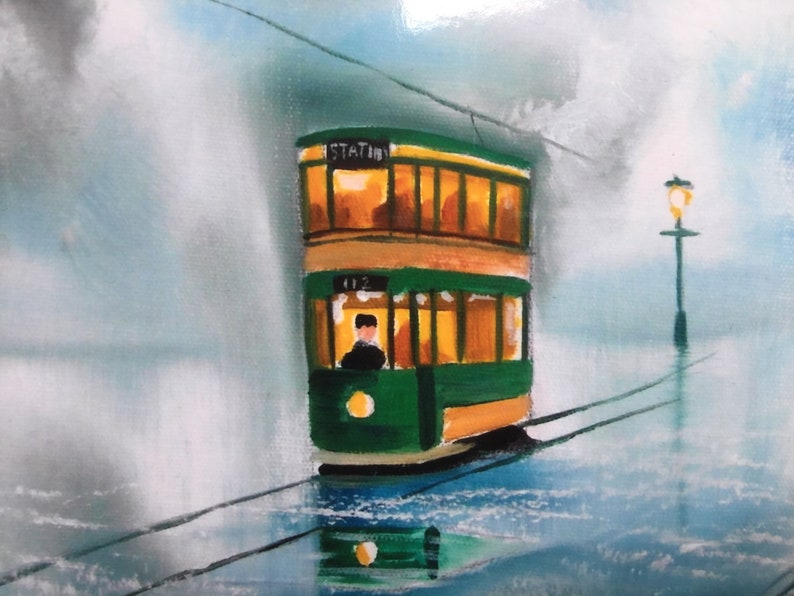 Puede incluir: Un tranv&iacute;a verde y amarillo de dos pisos con la palabra "STATION" en el lateral, viajando por un paisaje brumoso. El tranv&iacute;a tiene un solo pasajero visible en la ventana delantera.