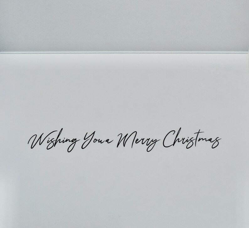 Puede incluir: Una tarjeta de felicitaci&oacute;n blanca con el texto "Wishing You a Merry Christmas" en elegante escritura negra. La tarjeta est&aacute; abierta, revelando un interior en blanco y un dise&ntilde;o simple y limpio, perfecto para mensajes navide&ntilde;os.