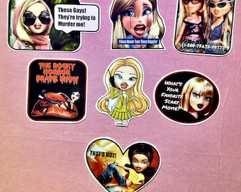 May include: A collection of colorful stickers featuring cartoon dolls and pop culture references. The stickers include text such as "These Gays! They're trying to Murder me!", "I Have Never Ever Been Happier", and "That's Hot!"