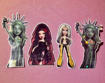 May include: Four Bratz doll stickers. Two dolls are styled as the Statue of Liberty, holding a torch. One doll wears a black dress and veil. The fourth doll wears a black top and yellow pants.
