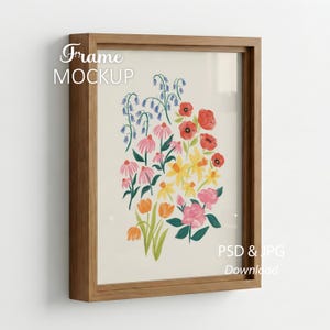 May include: A framed floral art print featuring a colorful bouquet of flowers in shades of red, pink, yellow, and orange. The frame is made of light brown wood. The text "Frame MOCKUP" is at the top left and "PSD & JPG Download" is at the bottom right.