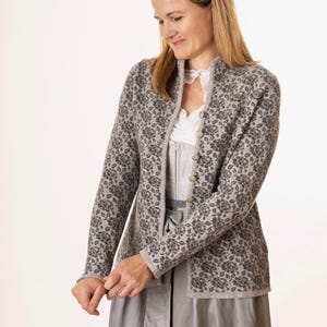 May include: A gray floral-patterned jacket with a mandarin collar and wooden buttons. The jacket is worn over a white lace-trimmed top and a gray dress. The floral pattern is a darker shade of gray.