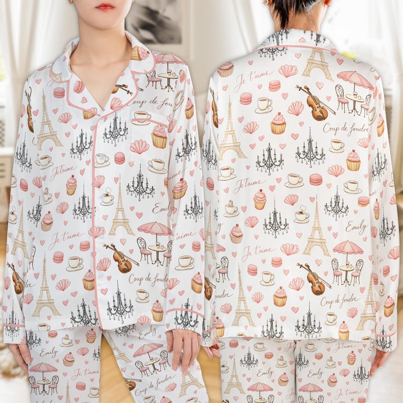 May include: White pajama set with a repeating pattern of Parisian icons, including the Eiffel Tower, chandeliers, and cafe scenes. The set is trimmed in pink and features the text "Je t'aime" and "Coup de foudre".
