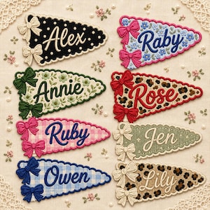 May include: Eight triangular fabric pennants featuring embroidered names including Alex, Raby, Annie, Rose, Ruby, Jen, Owen, and Lily. Each pennant has scalloped edges, two decorative fabric bows, and distinct patterns like polka dots, floral, gingham, and leopard print.