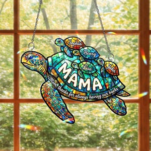 May include: A stained-glass style turtle suncatcher with the word "MAMA" in large white letters. The turtle has a mosaic design in shades of blue, green, and orange. Smaller turtles with names are on the back. The text reads "Mom, thanks for always having our backs."