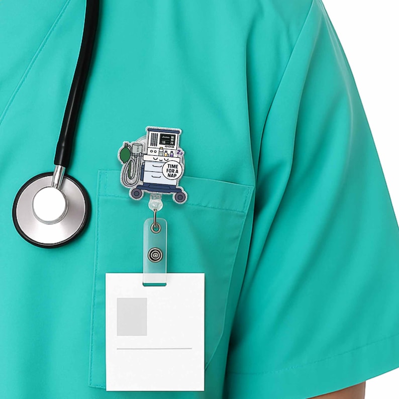 May include: A teal scrub top with a stethoscope and a badge reel with a cartoon medical machine that says "Time for a Nap".