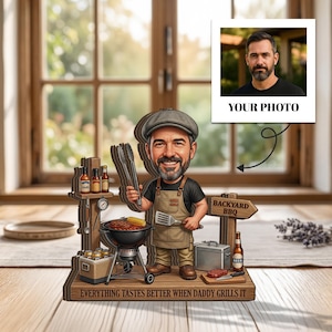 May include: A wooden BBQ-themed figurine depicting a cartoon man with a grill, tongs, and spatula. The figurine includes a sign that says "Backyard BBQ" and the text "Everything tastes better when daddy grills it."