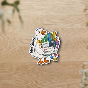 以下が含まれることがあります： 黄色い水玉模様のネッカチーフを巻いた白いガチョウのステッカー。I Love Mathと書かれた開いた本、電卓、地球儀、定規を持っています。左側にはMrs. Smithという文字とカラフルな数学記号が縦にプリントされています。