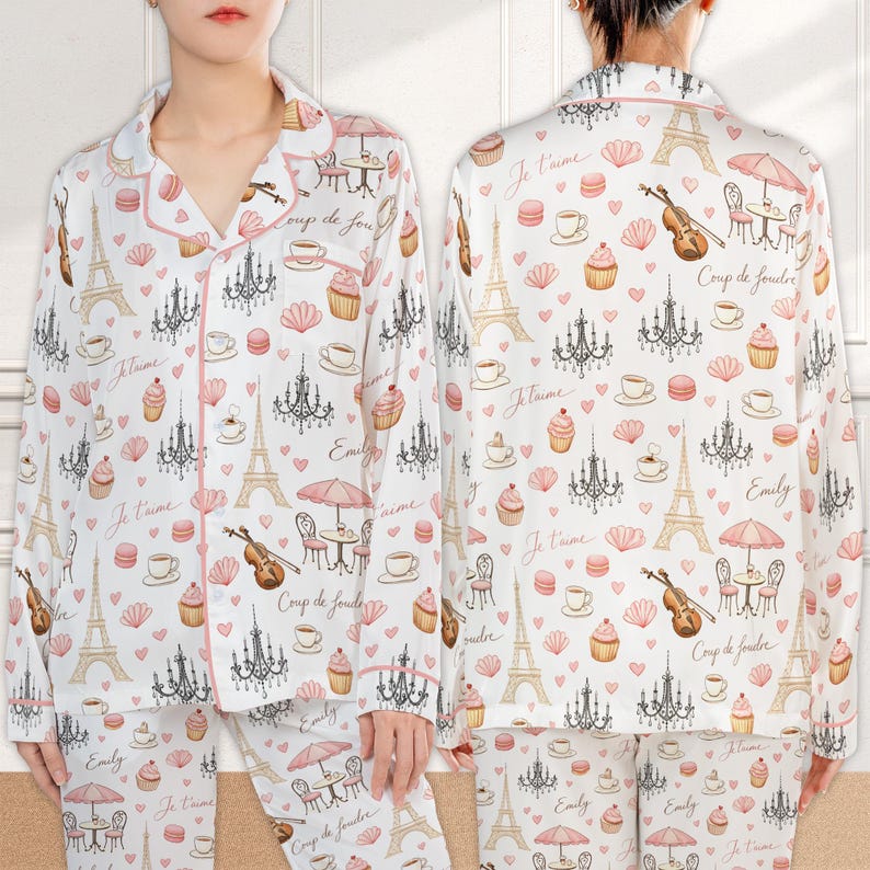 May include: White pajama set with a pink trim, featuring a repeating pattern of the Eiffel Tower, chandeliers, cupcakes, and coffee cups. The set includes a button-down top and matching pants. The words "Je t'aime", "Coup de foudre", and "Emily" are also printed on the pajamas.
