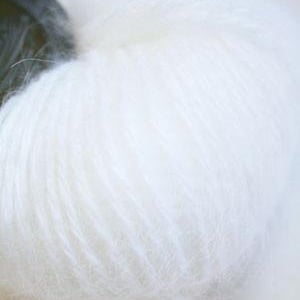 Puede incluir: Un ovillo de hilo blanco con una textura suave y esponjosa.
