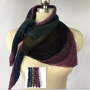 May include: A triangular shawl knitted in a gradient of blue, green, brown, purple, and pink yarn. The yarn is shown in skeins below the shawl.