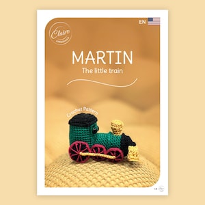 May include: A crochet pattern cover featuring a green, black, and red toy train. The text "MARTIN The little train" is displayed in white. The cover also includes the text "Crochet Pattern" and the Claire creations logo.