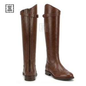 May include: Two brown leather riding boots. The boots have a tall shaft, a zipper in the back, and a buckle closure at the top. The boots have a classic design with decorative perforations on the toe.