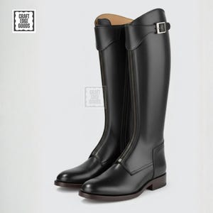 May include: A pair of black riding boots with a zipper closure and buckle detail. The tall boots have a smooth leather finish and a brown sole. The boots are designed for equestrian activities.
