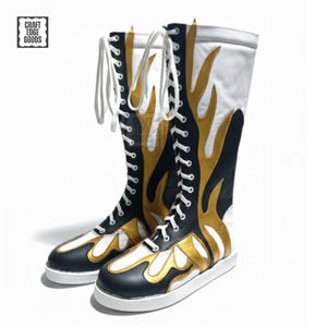 May include: A pair of tall, lace-up boots with a flame design. The boots feature a black, white, and gold color scheme. The boots have white laces and soles, with the text "CRAFT EDGE GOODS" in a square on the upper left.