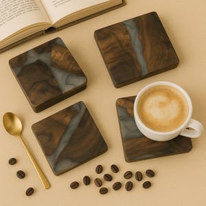 Puede incluir: Cuatro posavasos cuadrados de resina marrón y gris con un patrón de veta de madera. Los posavasos están sobre una superficie beige con una taza de café y granos de café.