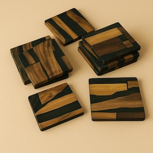 Puede incluir: Un conjunto de posavasos cuadrados de madera con un diseño geométrico. Los posavasos presentan una combinación de madera marrón oscuro y negra, creando un contraste llamativo. Los posavasos están dispuestos sobre una superficie beige claro.