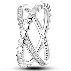 Op de afbeelding: Zilveren ring met een dubbelband ontwerp. Een band heeft een rij kleine, heldere stenen en de andere band heeft een rij ster-uitsnijdingen. De ring is gemarkeerd met "S925" aan de binnenkant.