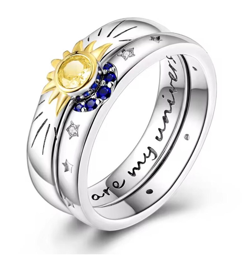 Op de afbeelding: Een zilveren ring met een gouden zonontwerp en blauwe edelstenen. De inscriptie op de band luidt "You are my universe".