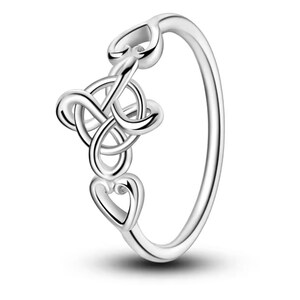 Op de afbeelding: Een zilveren ring met een delicaat ontwerp met in elkaar verweven harten en een kleine, heldere steen.
